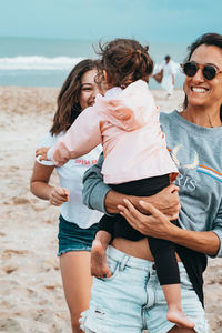 Happy mother carrying daughter while walking at beach