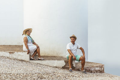 Senior tourist couple sitting on steps in a village, el roc de sant gaieta, spain