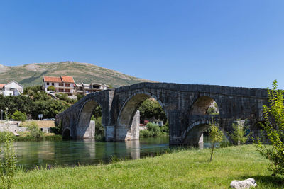 Arch bridge over river against clear sky