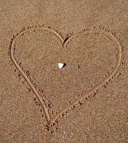 Close-up of heart shape on sand at beach