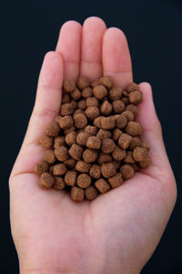 Cropped image of person holding bread against black background