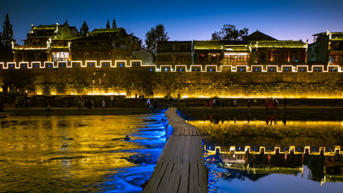 Reflection of buildings in lake at night