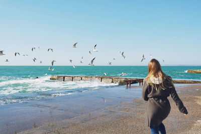 Rear view of woman on beach against sky