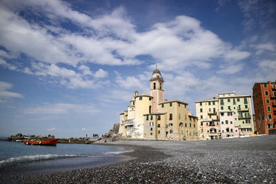 Buildings by sea against sky