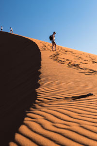 Man standing on sand dune against clear sky