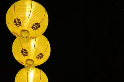 Low angle view of illuminated lantern hanging against black background
