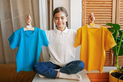 Girl chooses t-shirt among clothes at home. mockup friendly. t-shirts ready to have design