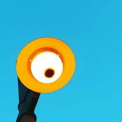 Low angle view of illuminated light bulb against blue sky
