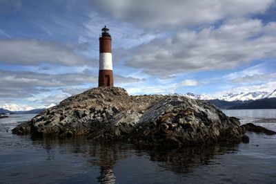 Lighthouse by sea against sky