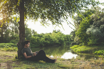 Man sitting by lake against trees
