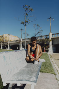 Full length of young man holding camera against sky