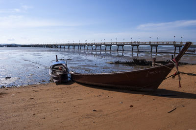 Boat moored on beach against sky