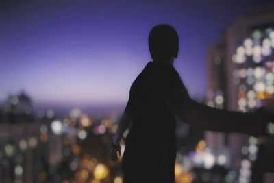 Silhouette man against illuminated city at night