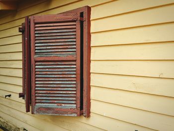 Open brown wooden window of yellow house