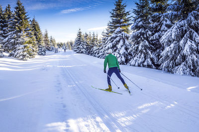 Rear view full length of man skiing on snow covered field