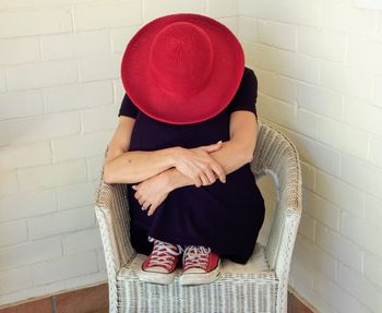 Midsection of woman wearing hat against wall