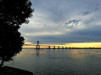 Bridge over calm river against sky