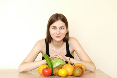 Portrait of woman with fruits against white background