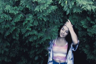 Woman with head in hand standing amidst leaves