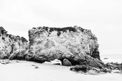 Rock formations on beach against clear sky