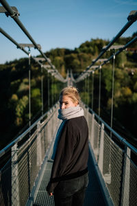 Portrait of woman on footbridge against sky