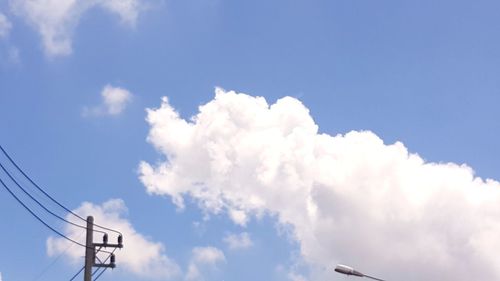 Low angle view of electricity pylon against cloudy sky