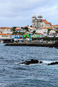 Buildings by sea against sky in city