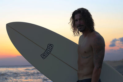 Man standing by sea against sky during sunset