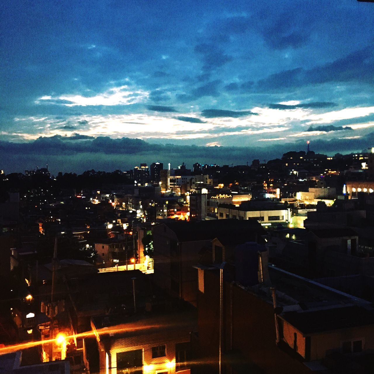 building exterior, illuminated, architecture, cityscape, built structure, city, sky, night, high angle view, residential building, cloud - sky, crowded, residential district, dusk, residential structure, city life, dark, cloud, outdoors, no people