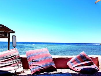 Deck chairs on beach against clear blue sky