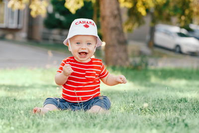 Portrait of cute baby boy sitting on grass