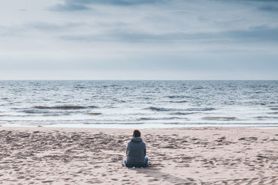 Rear view of man looking at sea against sky