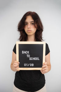 Portrait of young woman using laptop while sitting against white background