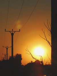 Low angle view of silhouette electricity pylon against romantic sky