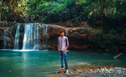 Man standing by waterfall against trees