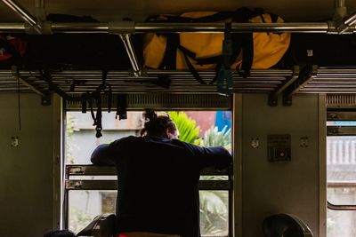 Rear view of man looking through train window