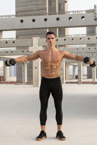Muscular shirtless man exercising outdoors