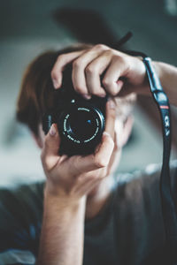 Midsection of person holding camera at home