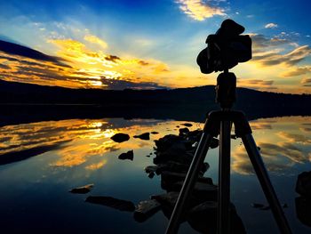 Close-up of silhouette camera against sky during sunset