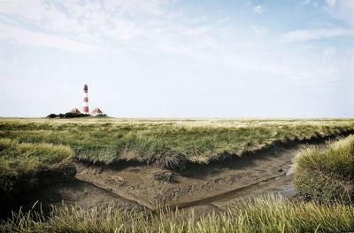 Lighthouse on field against sky