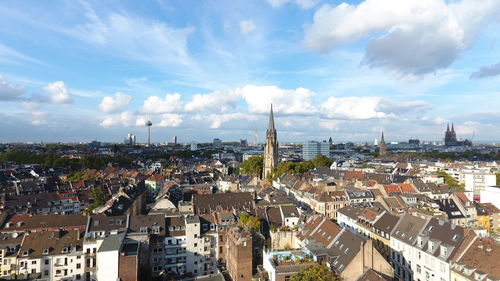 High angle view of city buildings against cloudy sky