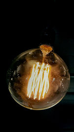 Close-up of illuminated light bulb against black background