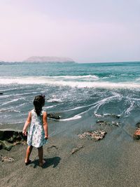 Full length of girl standing on beach against sky