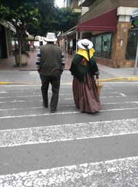 Rear view of people walking on street in city