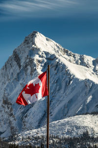 Red flag on snowcapped mountains against sky