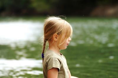 Side view of girl standing against lake