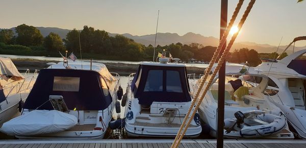 Boats moored at shore against sky during sunset