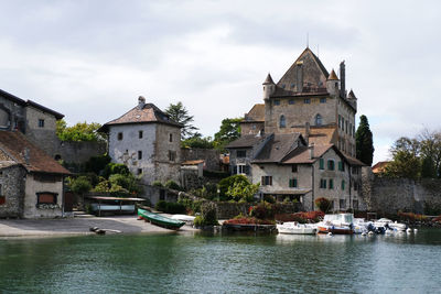 Buildings at waterfront against cloudy sky