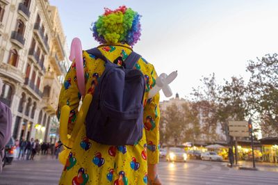 Rear view of man standing on street against sky