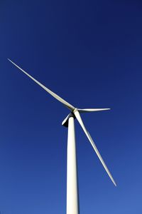 Low angle view of windmill against clear blue sky